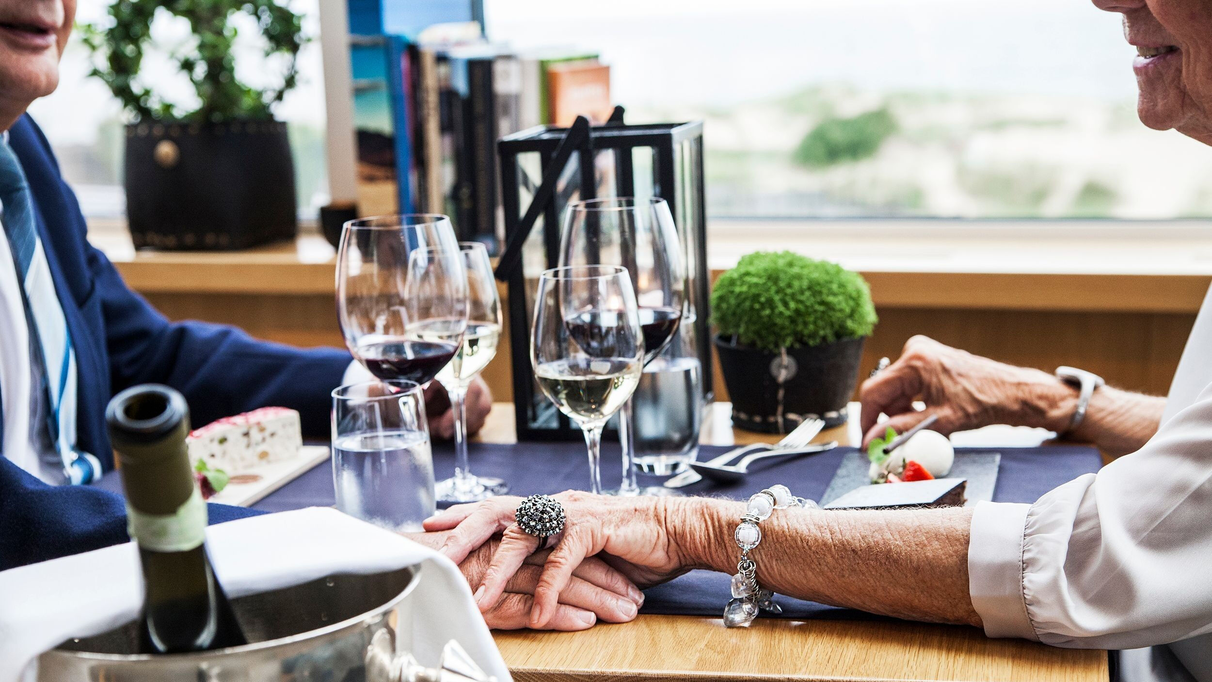 Ett äldre par som håller hand över ett restaurangbord