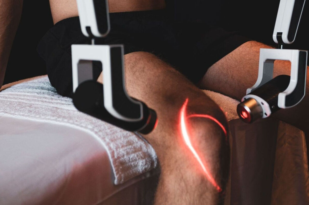 Man som behandlas med röd laser på sitt knä