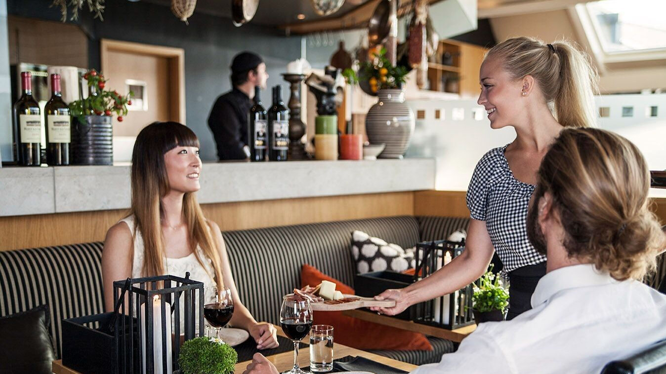 Hotel Tylösand servitris serverar mat till leende kvinna i restaurangen