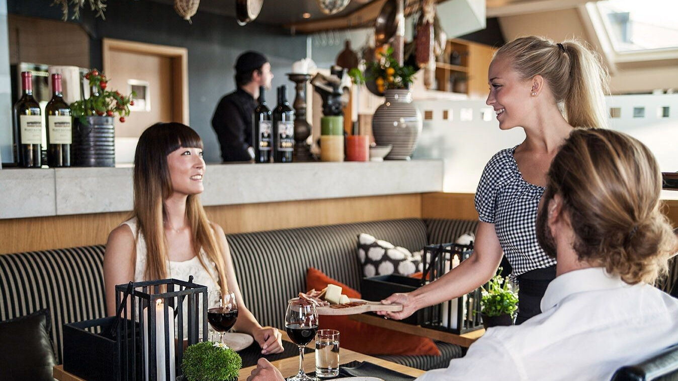 Hotel Tylösand servitris serverar mat till leende kvinna i restaurangen