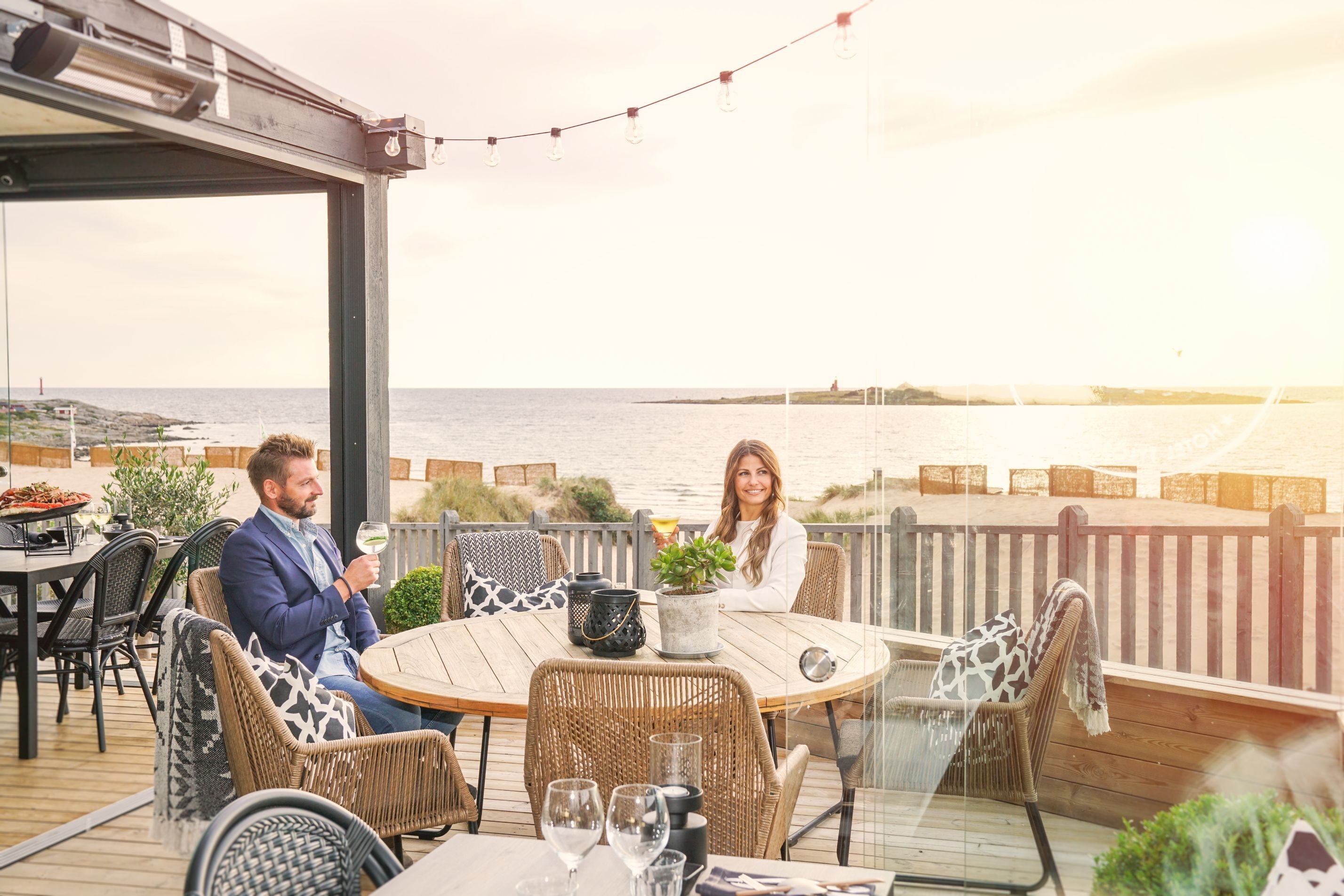 Ett par som sitter på Tylösands uteservering med utsikt mot havet