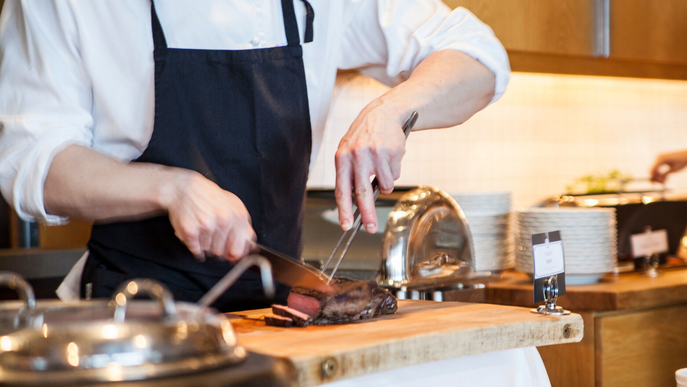 Kock på Hotel Tylösand trancherar kött.