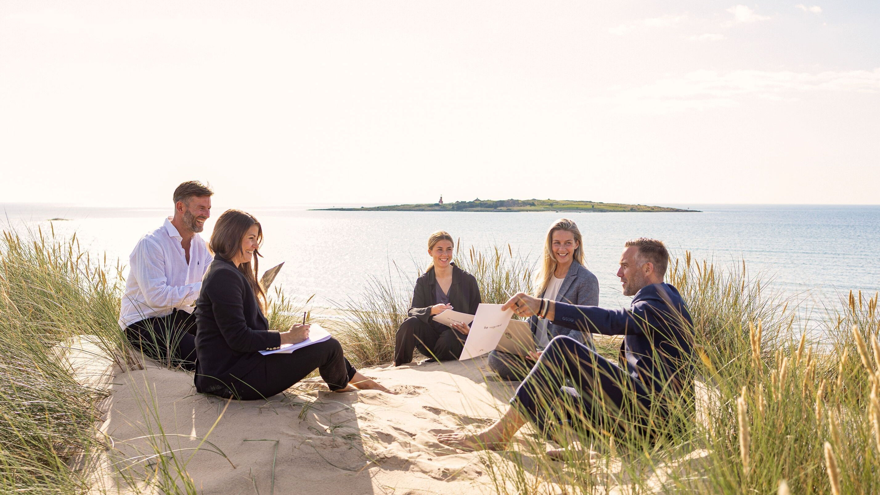 Konferensgrupp sitter i sanddynorna i Tylösand.