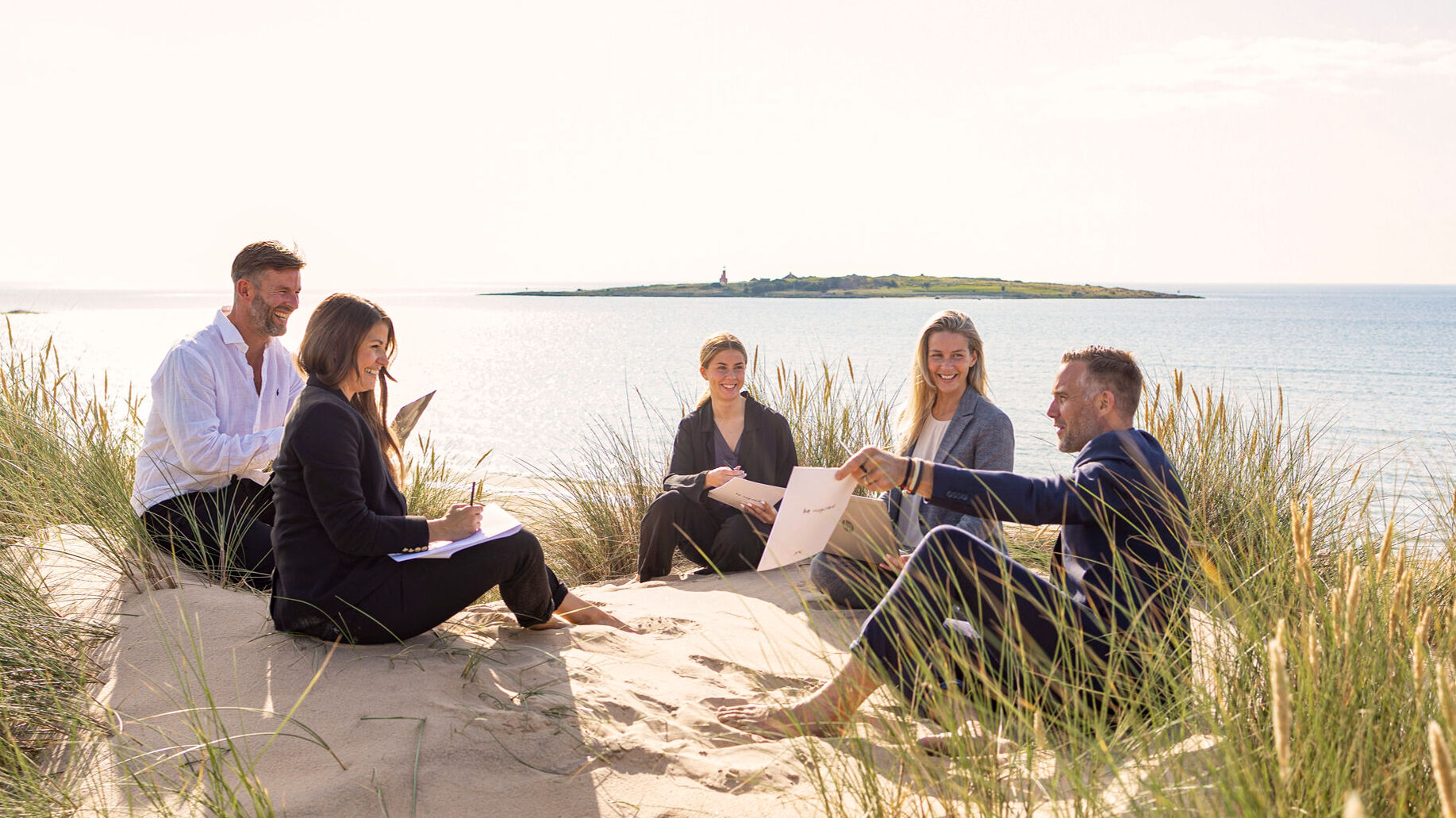 Konferensgrupp sitter i sanddynorna i Tylösand.