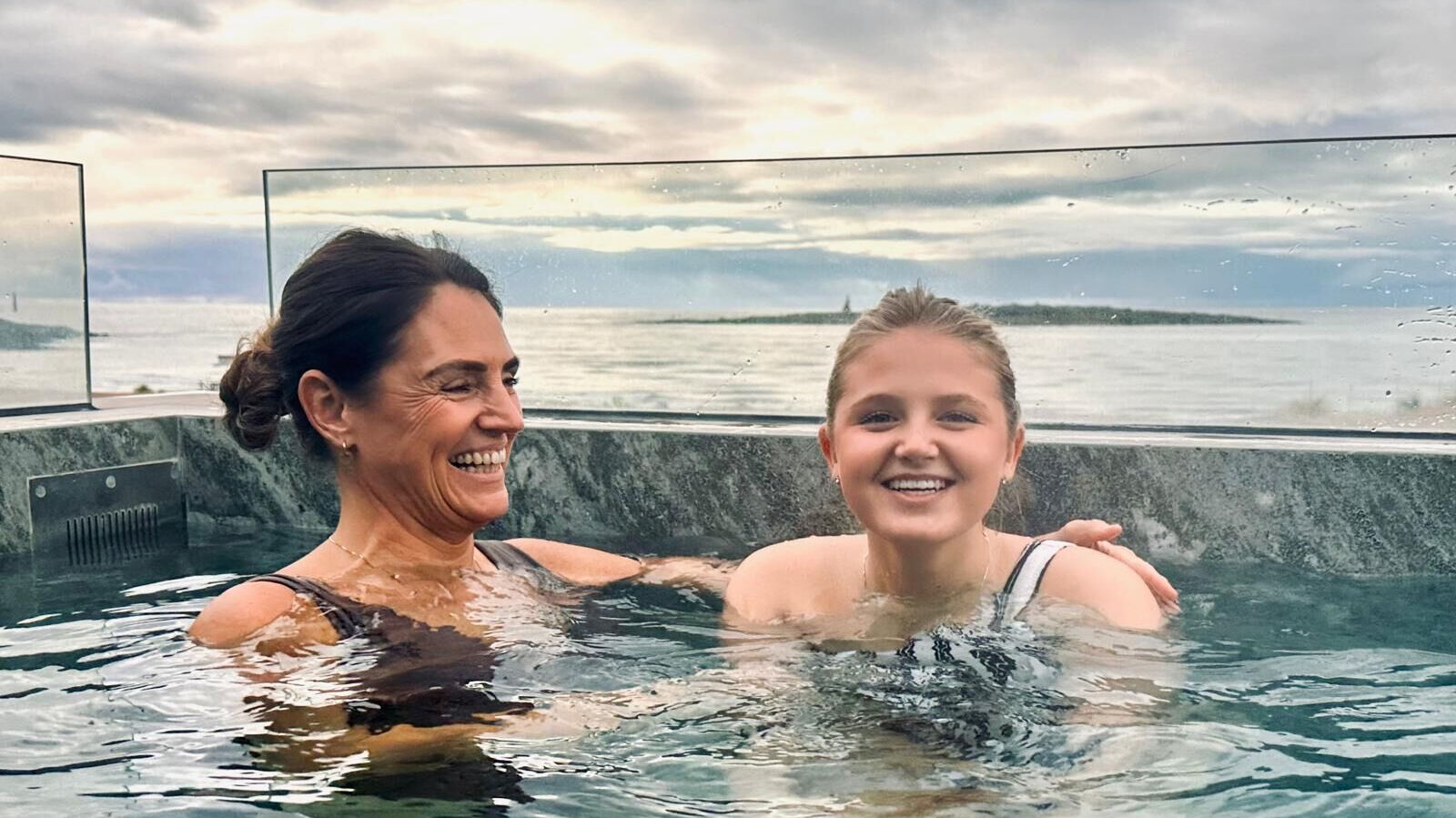 Mamma och dotter badar i utomhuspool i Tylösand vid havet.