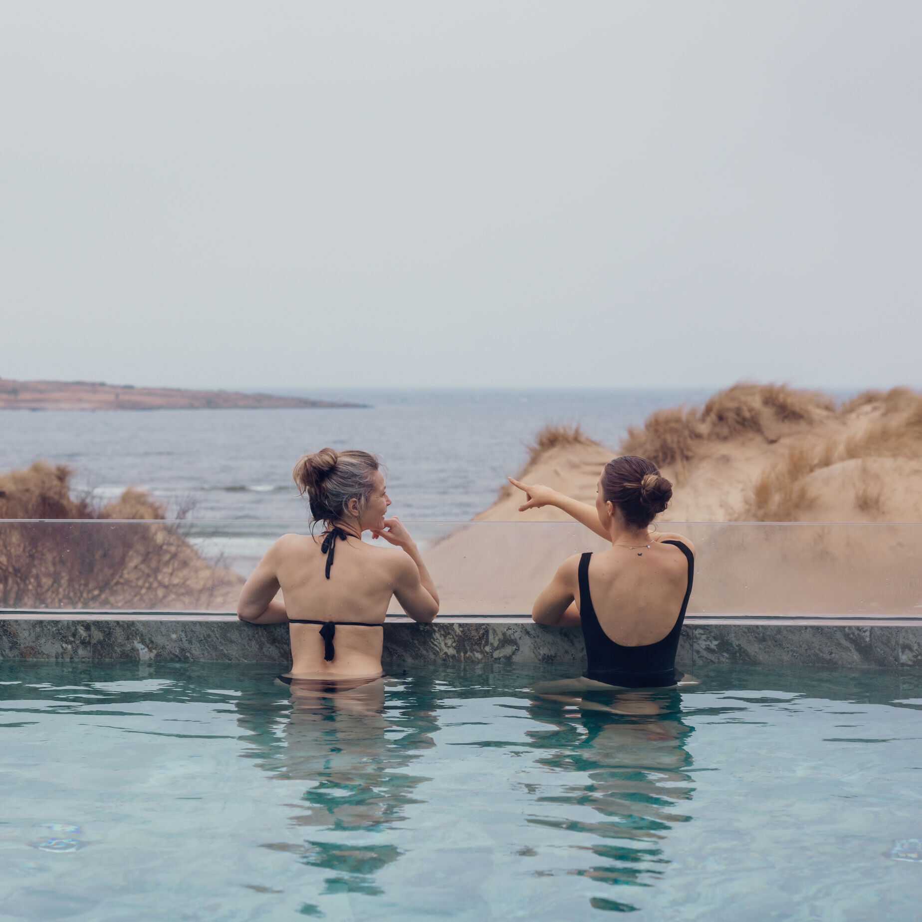 Två kvinnor badar i en utomhus pool.