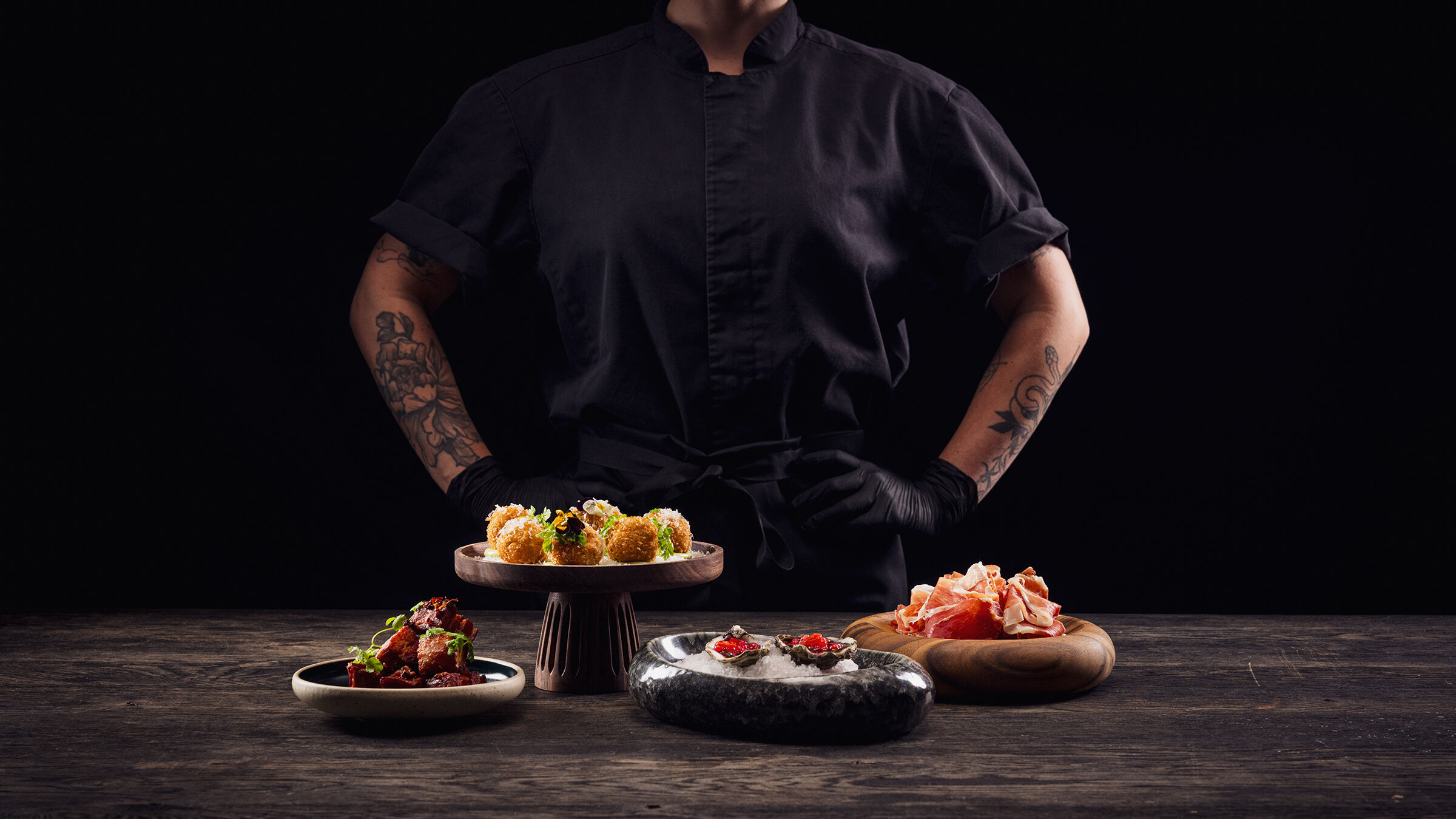 En kvinnlig kock står bakom fyra olika maträtter.