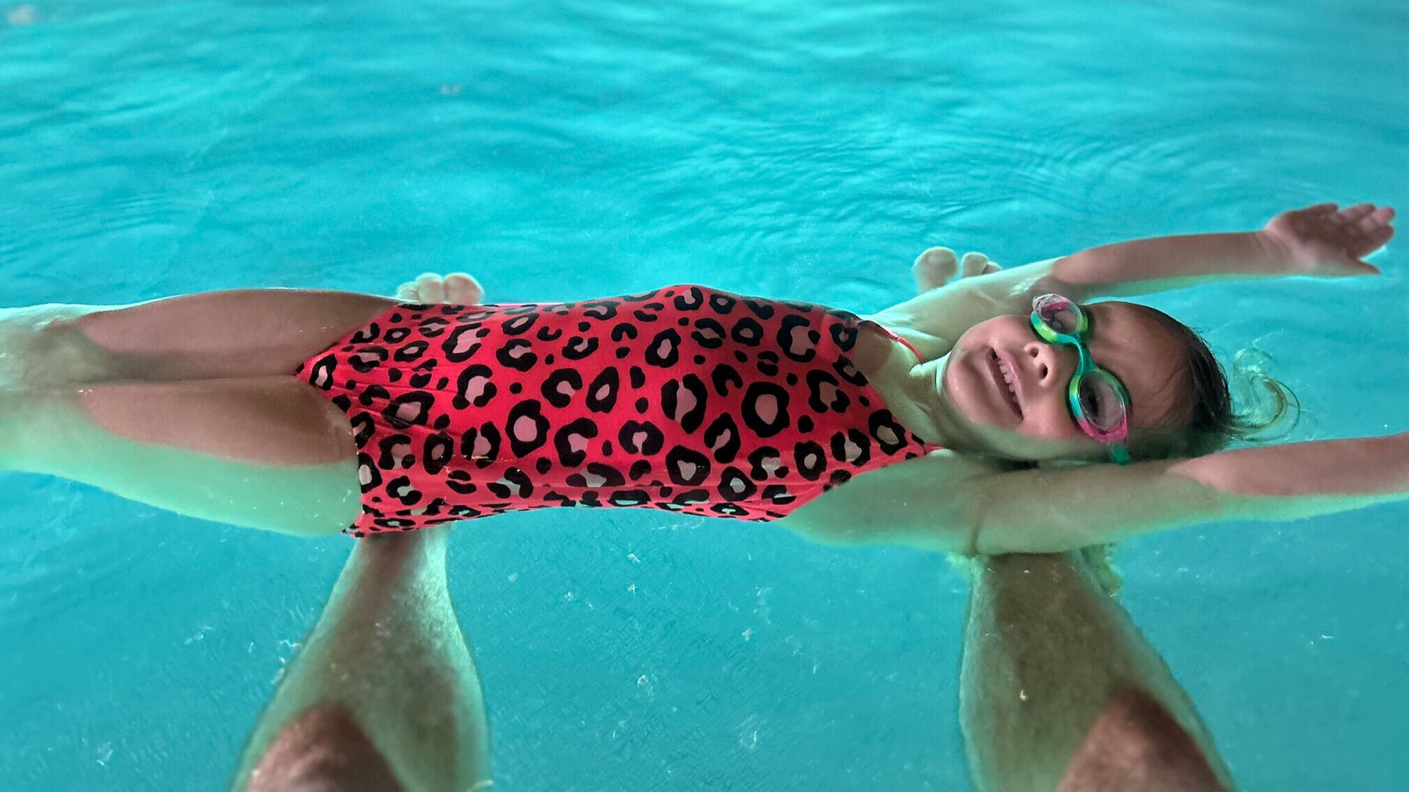 En liten tjej flyter i en pool.