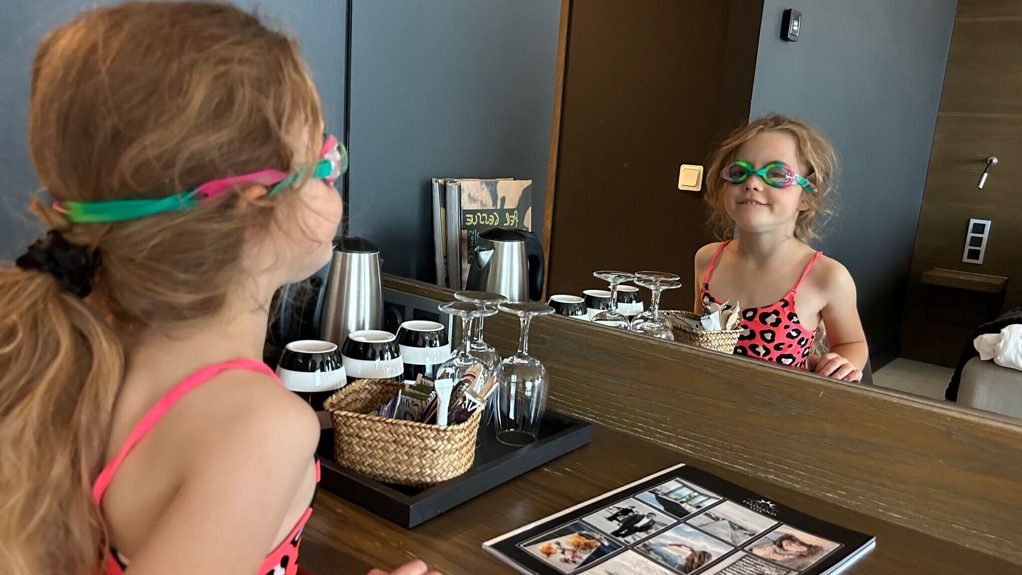 Liten tjej som tittar sig spegeln med simglasögon.