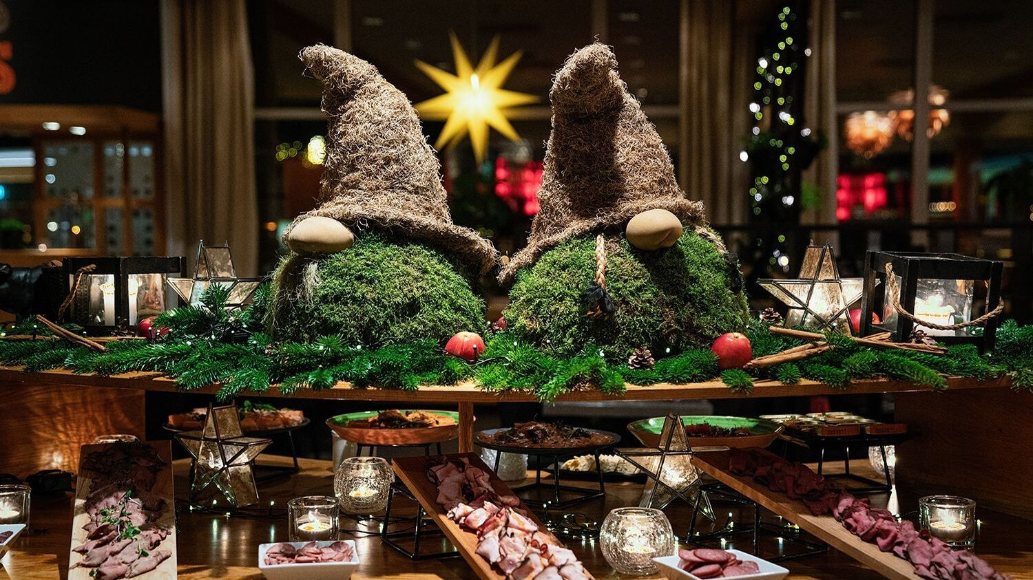 Två troll gjorda av mossa på ett julbord med skinka