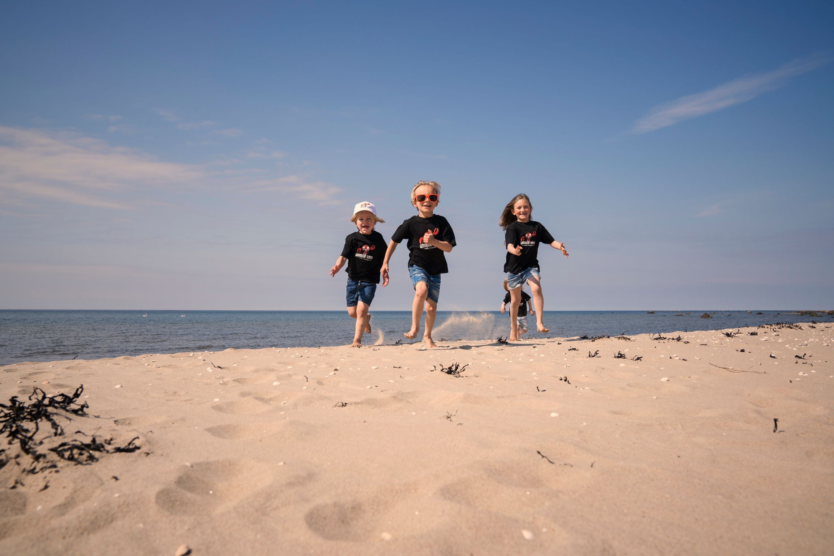 Fyra barn som springen på stranden i Tylösand