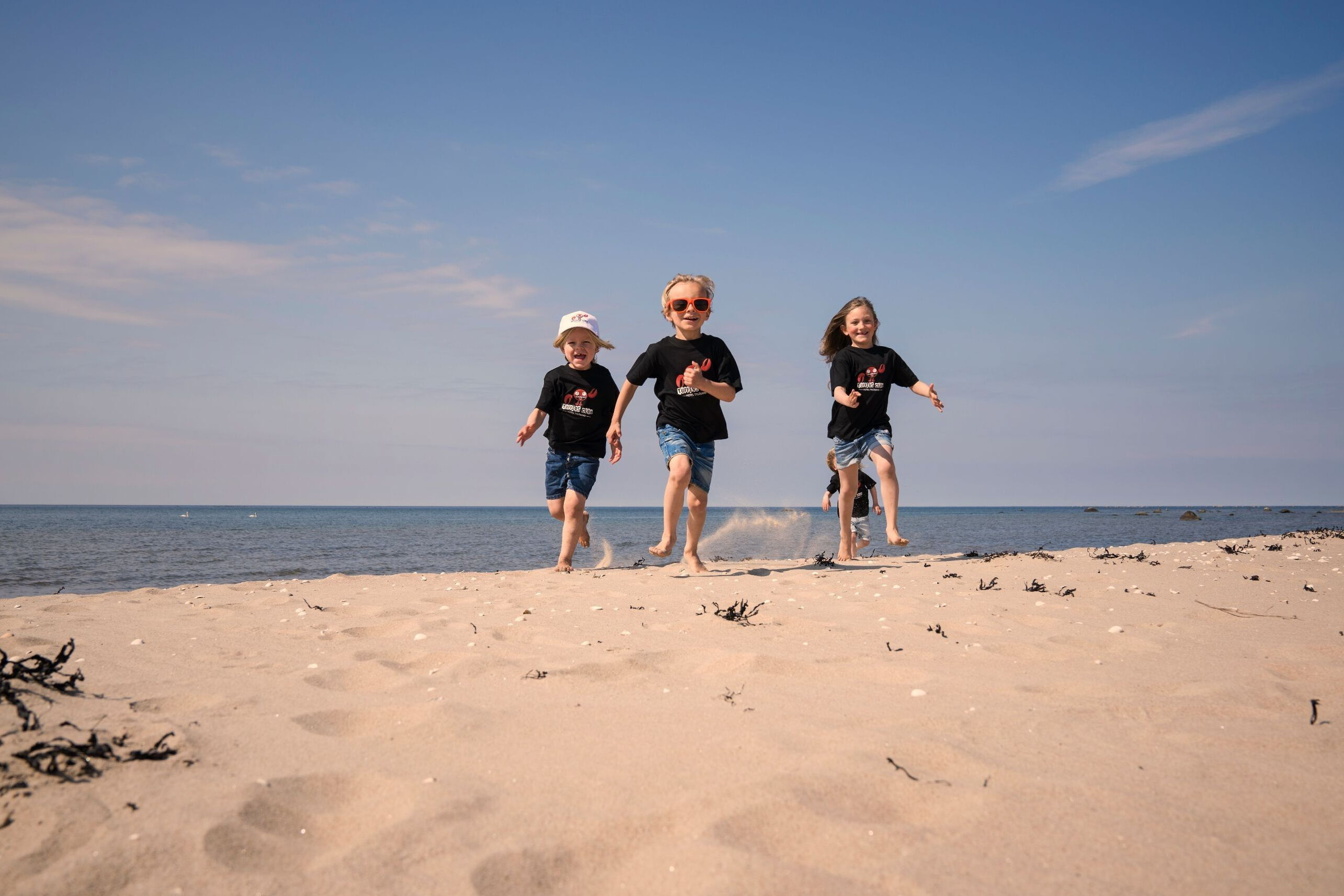 Fyra barn som springen på stranden i Tylösand