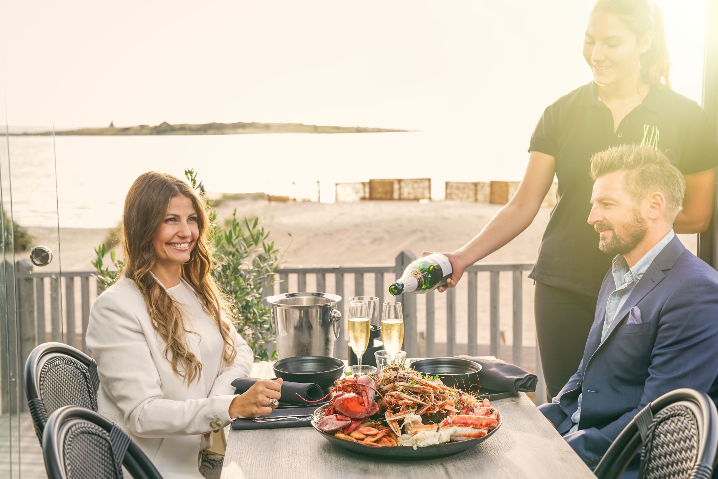 En kvinna och en man som blir serverade vin på en uteservering