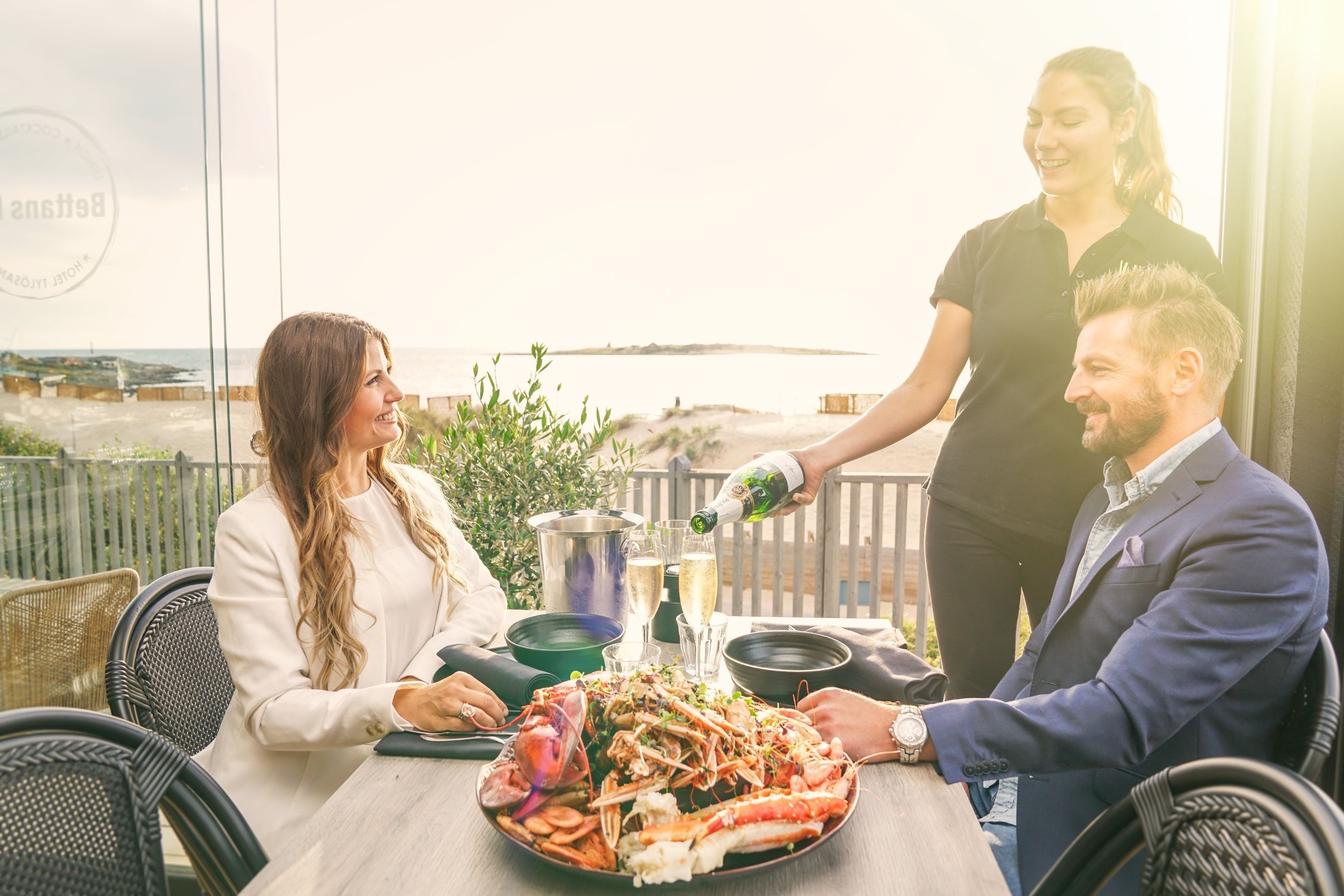 En kvinna och en man som blir serverade vin på en uteservering