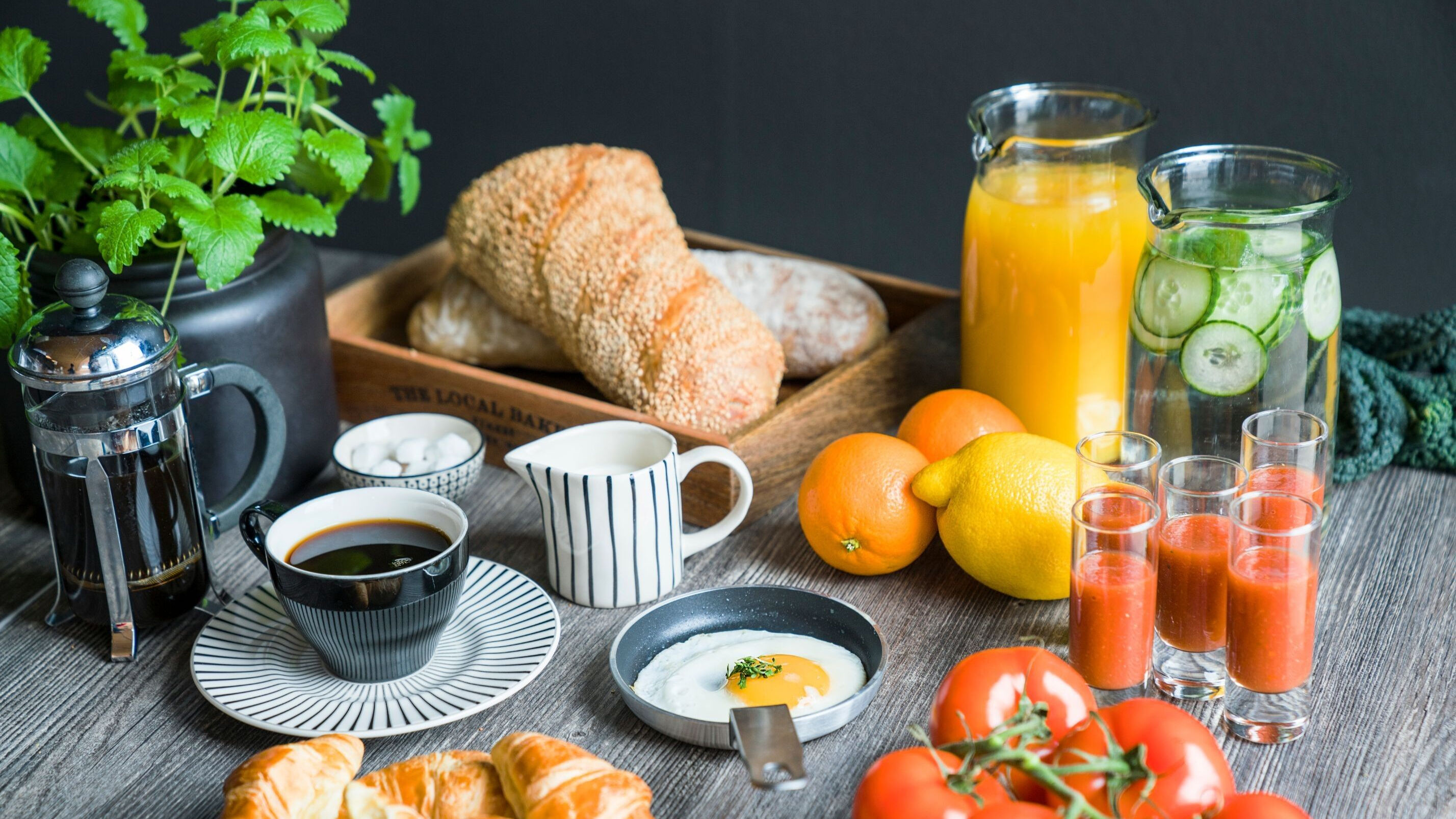 Ett frukostbord med kaffe, juice, grönsaker, bröd och ägg