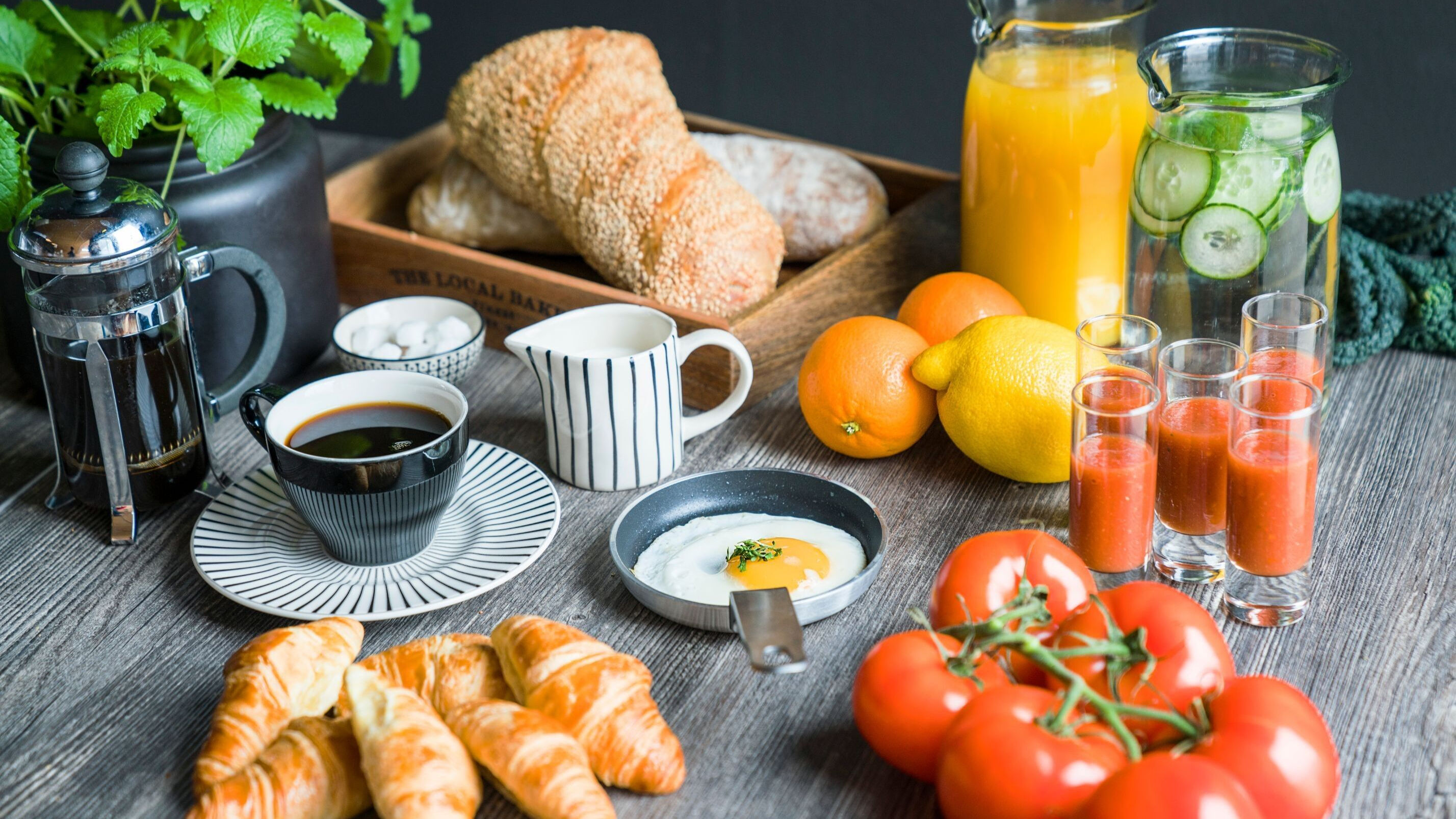 Frukostbord med juice, kaffe, bröd, croissanter och grönsaker