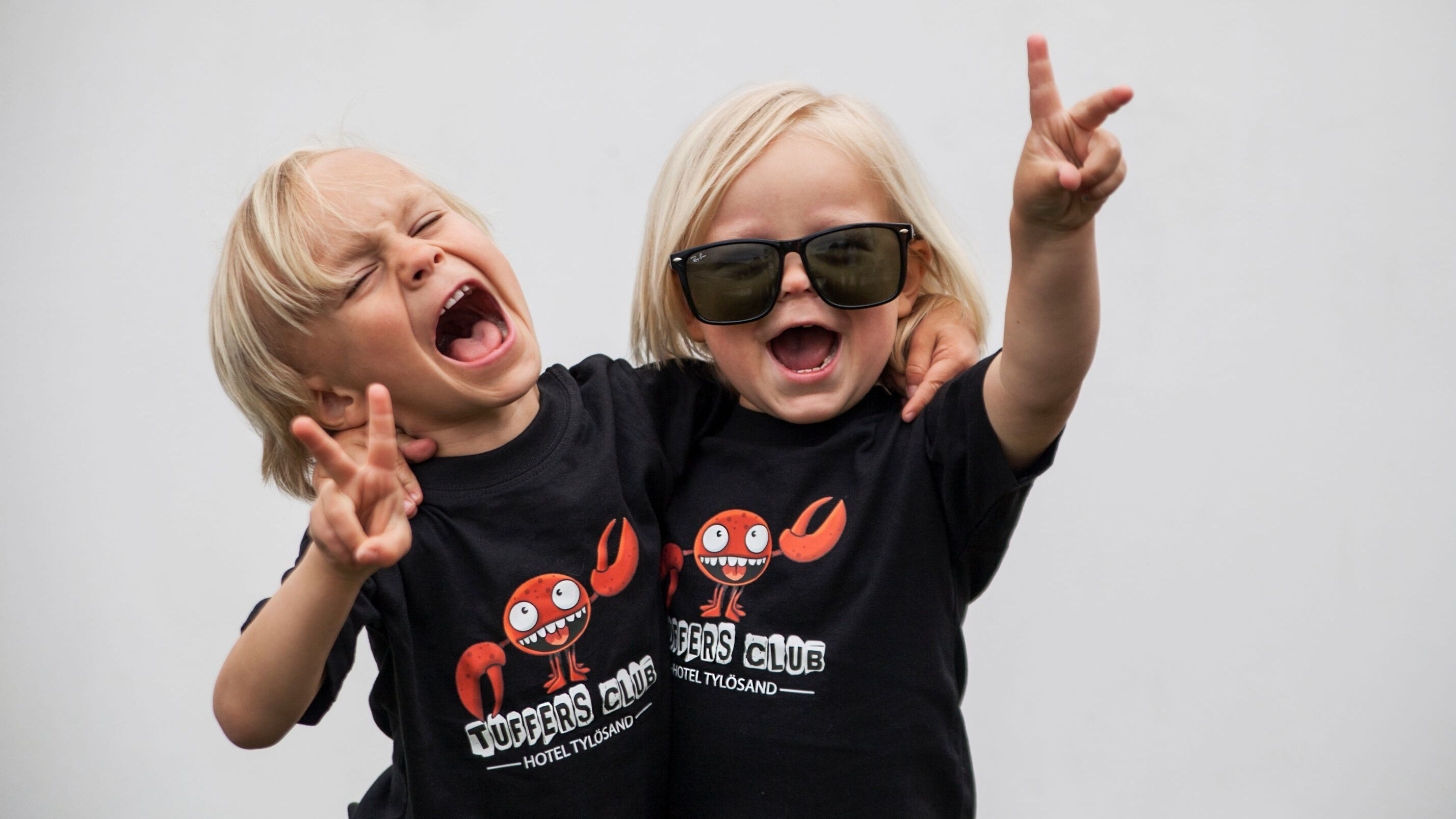 Två glada små barn som bär Tuffers Club T-shirts